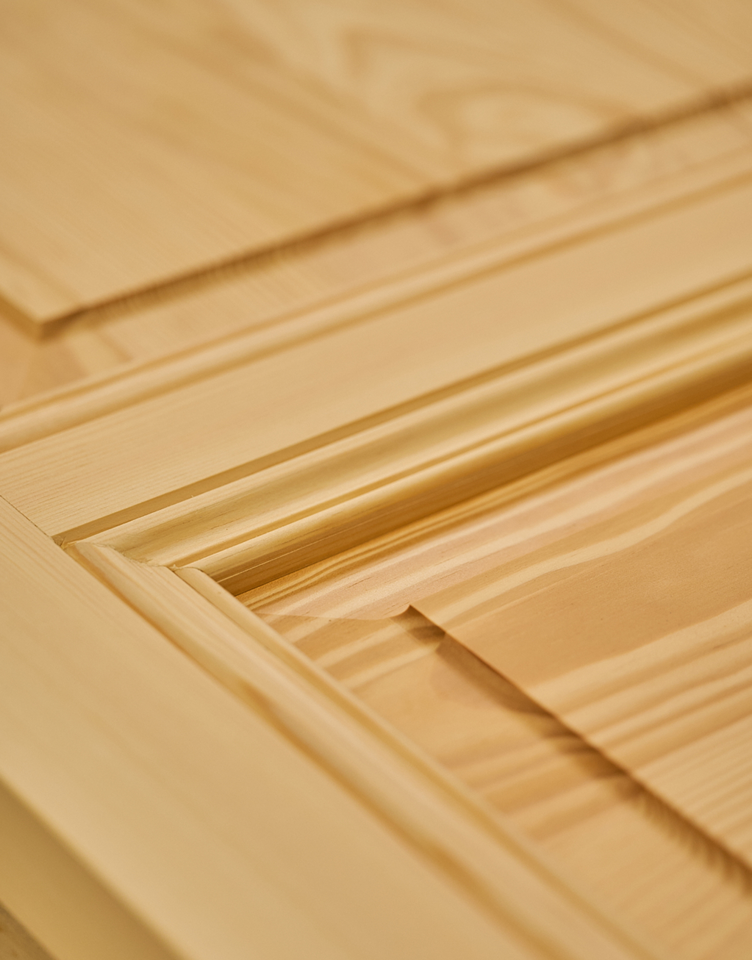 Gros plan sur un panneau de porte en bois clair avec détails sculptés.