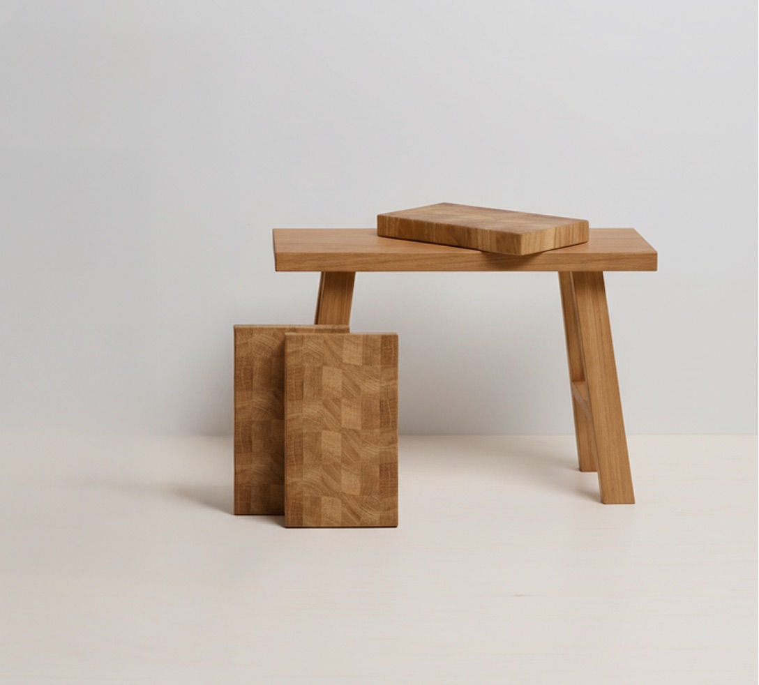 Quatre planches à découper en bois naturel avec une grande posée sur une table à trois pieds et trois plus petites disposées devant.